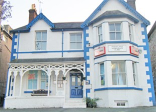 A two-story, white building with blue trim displays signs reading  A two-story, white building with blue trim displays signs reading