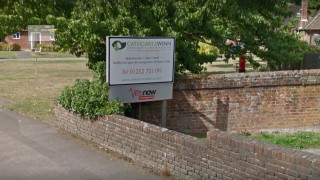 A veterinary clinic sign stands beside a brick wall under a tree. Text reads:  A veterinary clinic sign stands beside a brick wall under a tree. Text reads: