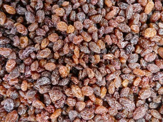 Clusters of brown raisins are densely packed together, filling the entire frame, creating a textured surface.