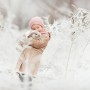 how to keep your rabbit warm in winter Child in a beige coat and pink hat hugs a fluffy rabbit in a snowy, frost-covered field.