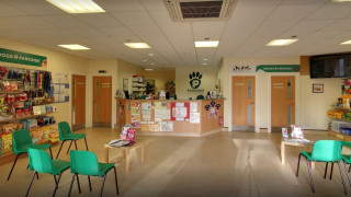 Reception desk with Parkside logo, surrounded by pet supplies on shelves. Green chairs and a table with brochures fill the waiting area. Signs read:  Reception desk with Parkside logo, surrounded by pet supplies on shelves. Green chairs and a table with brochures fill the waiting area. Signs read: