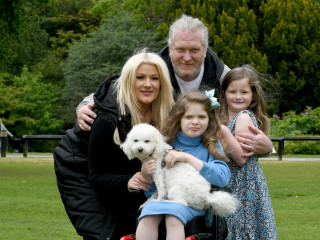 An image of a family and pet dog together for a picture in a field