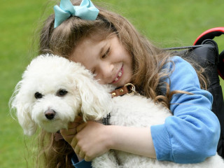 An image of a young girl cuddling her pet dog