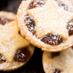 Close-up of traditional mince pies topped with star-shaped pastry and a dusting of icing sugar.