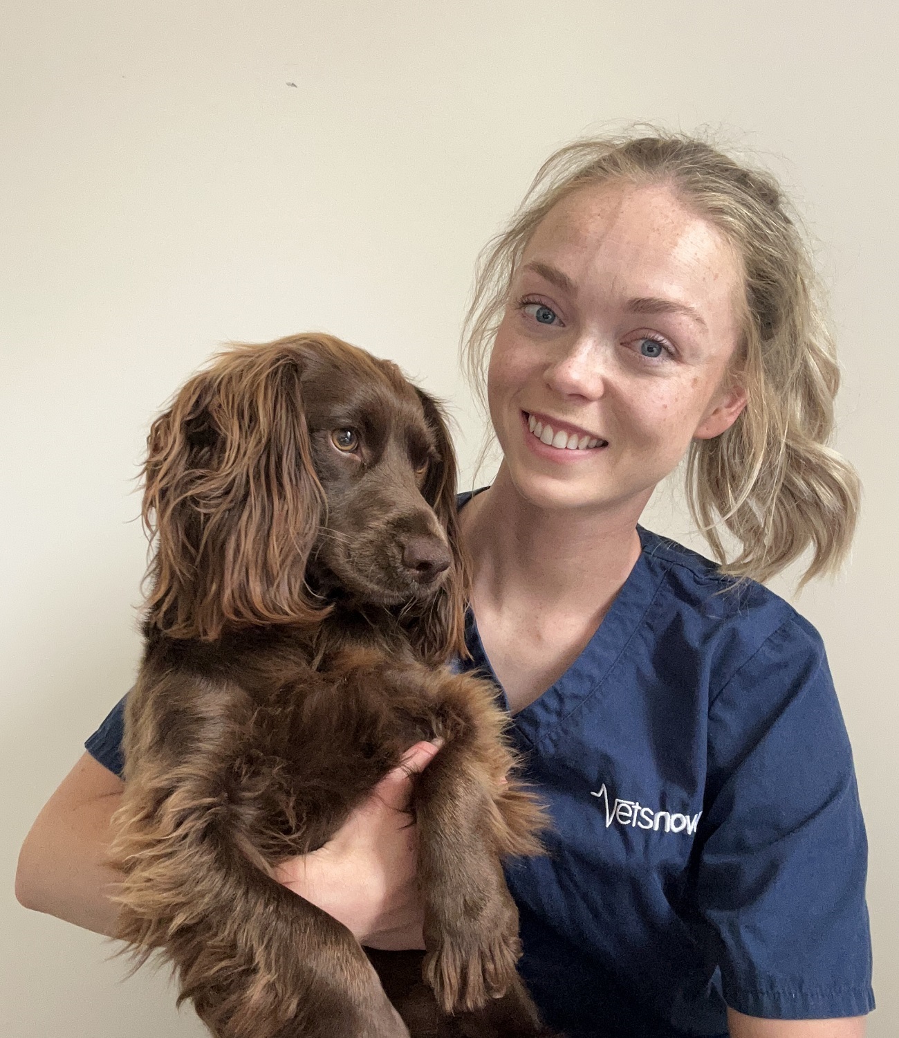 harriet-robinson-and-dog-vets-now Vets Now veterinary professional Harriet Robinson smiling while holding a brown spaniel dog