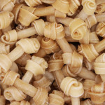 Close up of mutliple rawhide chews stacked on a pile.