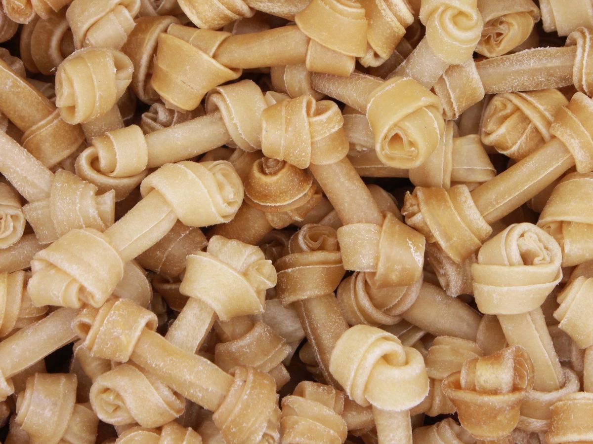 Close up of mutliple rawhide chews stacked on a pile.