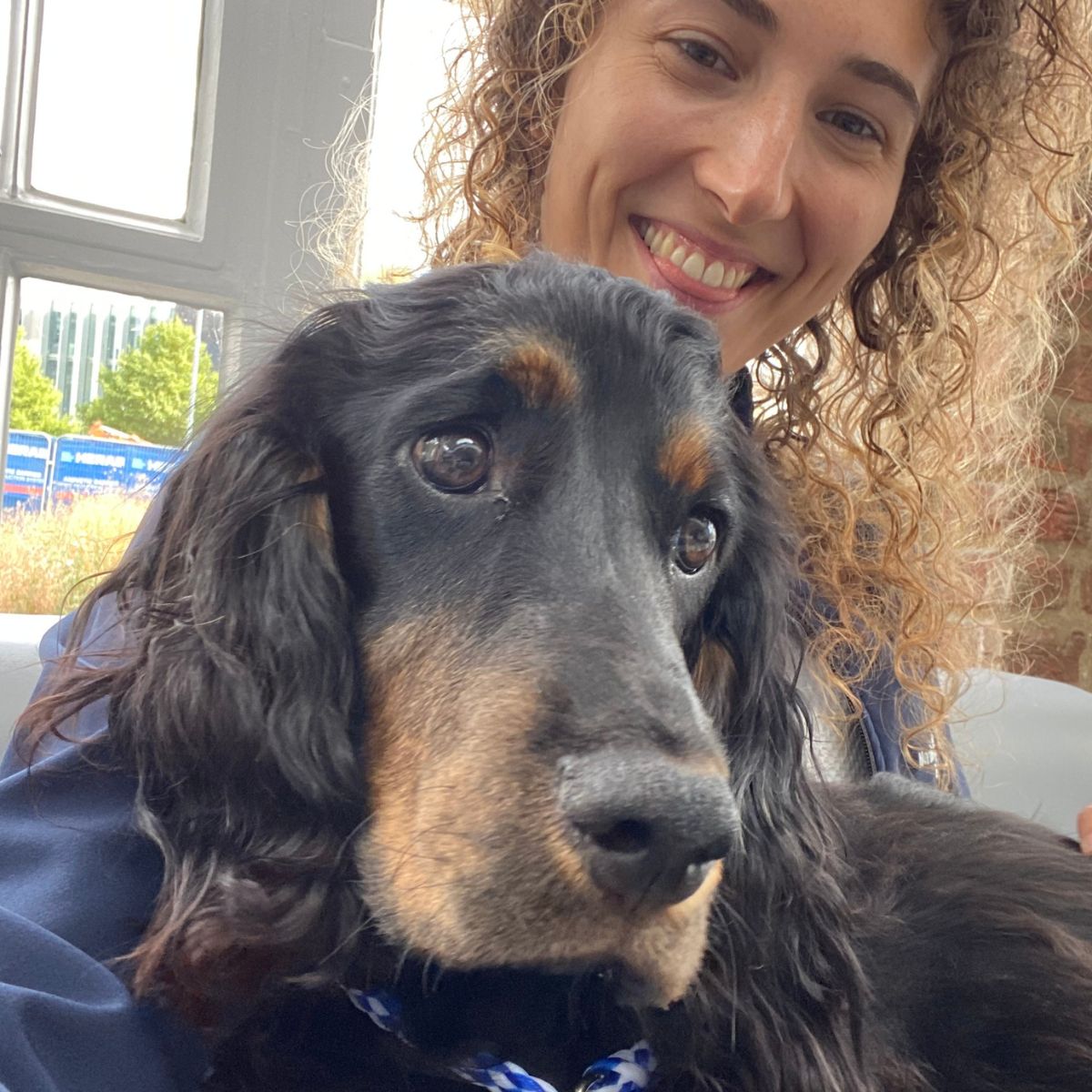 Woman smiling with Gin, a black and tan Gordon Setter puppy, indoors