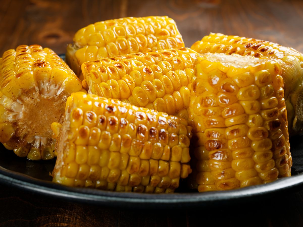 A tray of various pieces of grilled corn on the cob