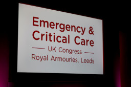 A large screen displays the text: “Emergency & Critical Care - UK Congress - Royal Armouries, Leeds” in red, set against a dark background.