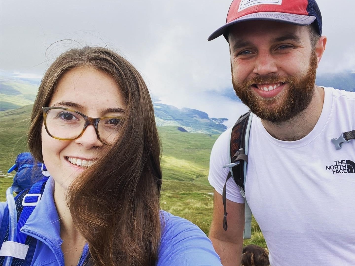 Cutting Edge graduate Sam Fielding Two people smiling in close-up, wearing outdoor gear, with a mountainous landscape in the background. One person has a backpack. Text on a shirt reads “THE NORTH FACE.”
