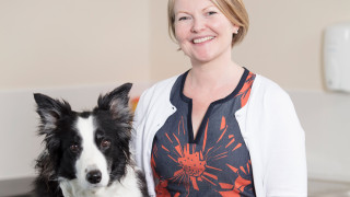 Tricia smiling with a border collie by her side
