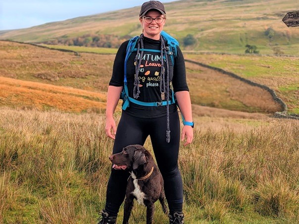 Vets Now Abby Wharton standing in a field with her dog.