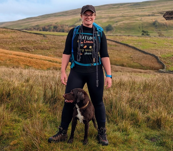 Vets Now Abby Wharton standing in a field with her dog.