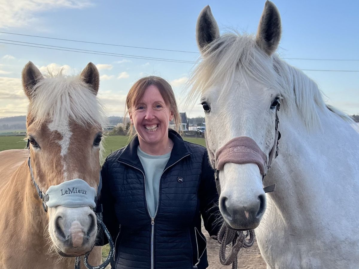 fiona-mcleod-with-horses Fiona McLeod smiling while standing with two horses in a field.