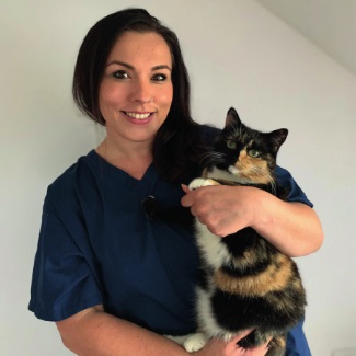 veterinary-nurse-yasmin-amer-with-a-cat Vets Now veterinary nurse Yasmin Amer smiling and holding a cat.