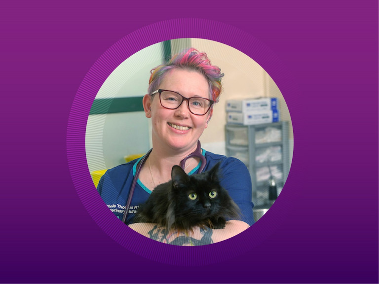 Vet smiling and holding a black cat at a Vets Now clinic